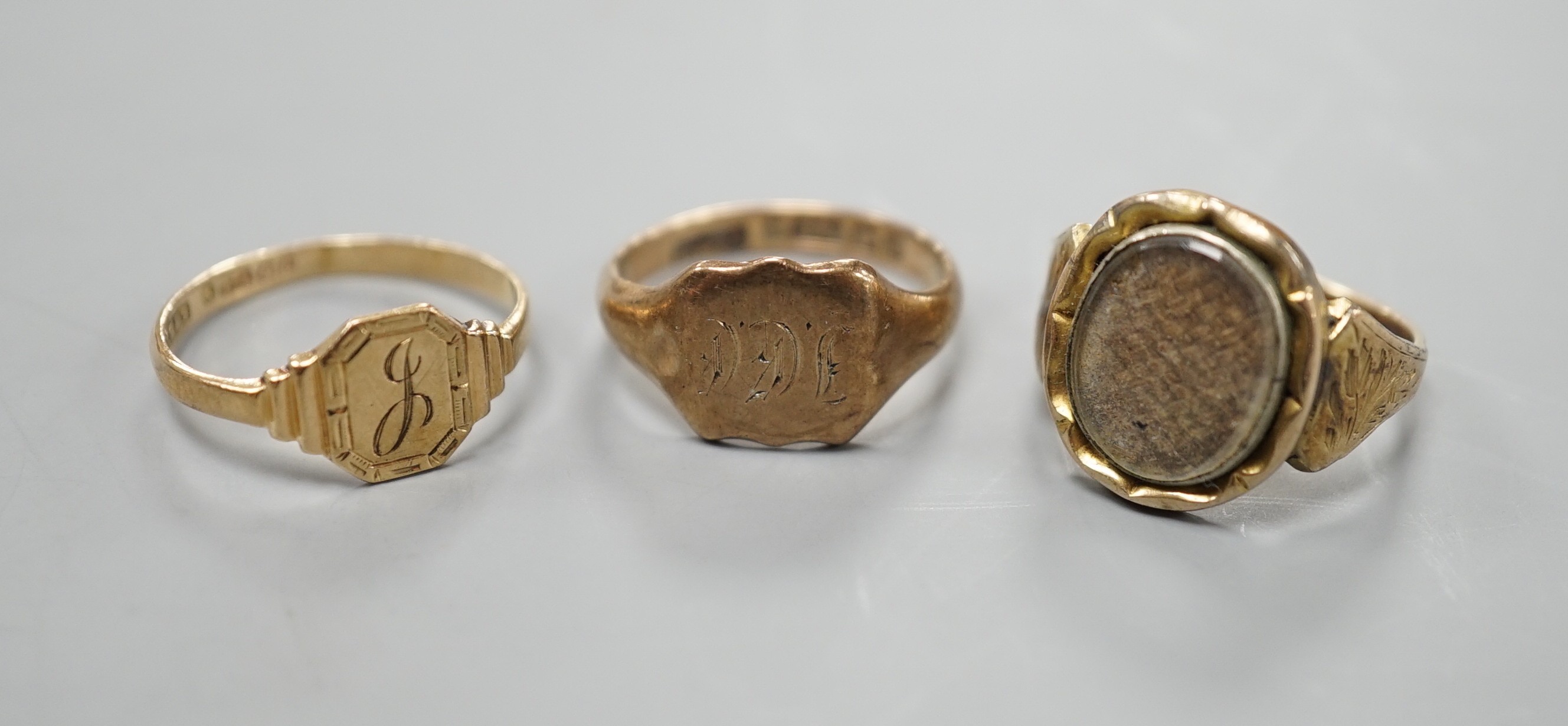 A 19th century yellow metal mourning ring, with plaited hair beneath a glazed panel size L, together with two later 9ct gold signet rings, gross weight 6.3 grams.